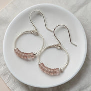 Silver hoop earrings with pink beads on a white plate