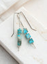 Turquoise beaded earrings on a white stone surface