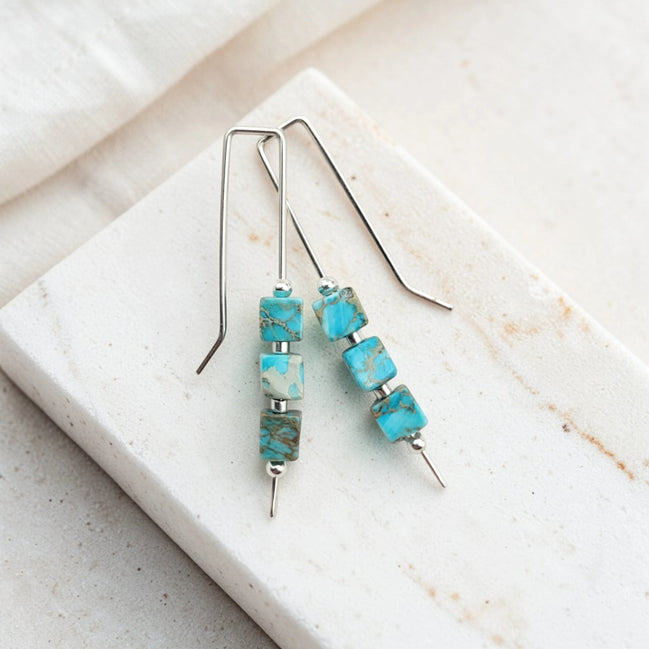 Turquoise beaded earrings on a white stone surface