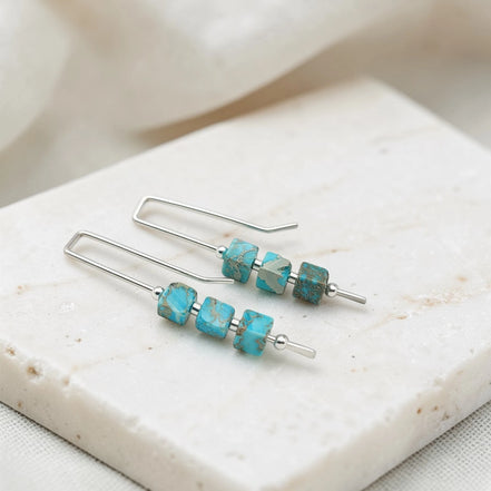 Turquoise beaded earrings on a marble surface