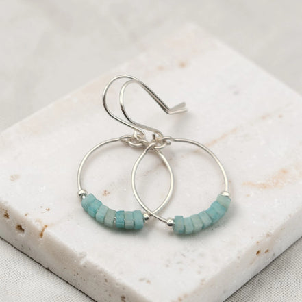 Silver hoop earrings with amazonite beads on a marble surface