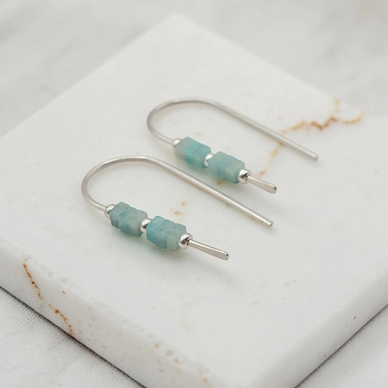 Silver earrings with amazonite beads on a marble surface