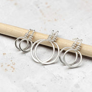 set of three handmade sterling silver hoop stud earrings on a concrete surface