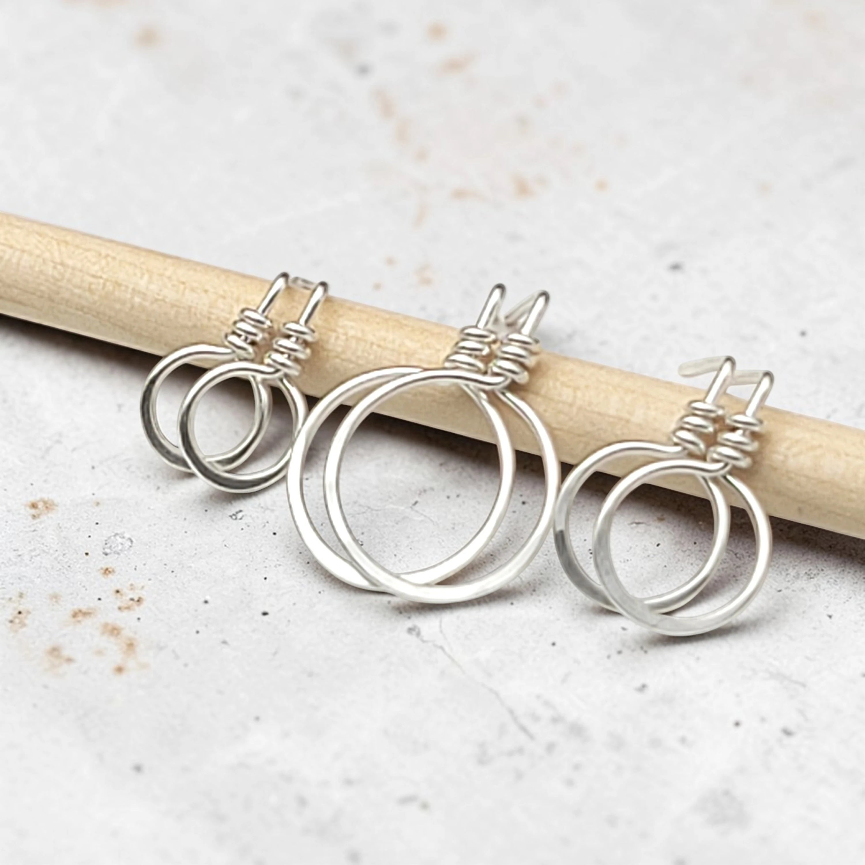 set of three handmade sterling silver hoop stud earrings on a concrete surface