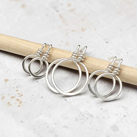 set of three handmade sterling silver hoop stud earrings on a concrete surface
