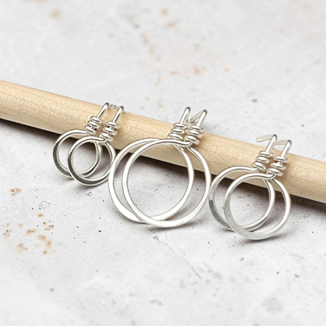 set of three handmade sterling silver hoop stud earrings on a concrete surface