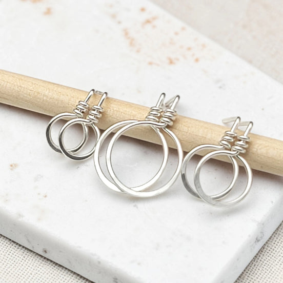 set of three handmade sterling silver hoop stud earrings on a concrete surfacte