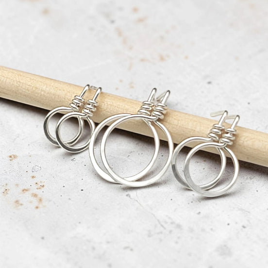 set of three handmade sterling silver hoop stud earrings on a concrete surface