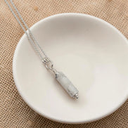 Necklace with a pendant on a white dish against a beige background
